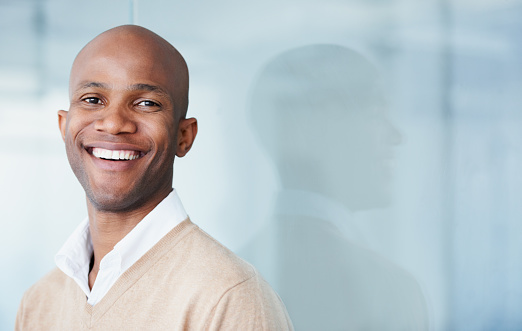 Young man smiling on a blue back-ground after dental bonding treatment by Hunter Dental Care in Portland, OR